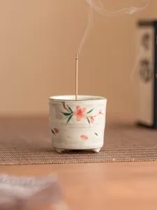 Bruciatore di incenso a treppiede in ceramica con fiori di pesco per decorazione.