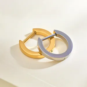 Gedetailleerde close-up van minimalisten D-vormige titanium creolen in goud en zilver afwerking.