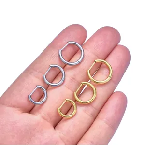 Gedetailleerde close-up van titanen D-ring oorringen en lichaamspiercing sieraden in zilver en goud.