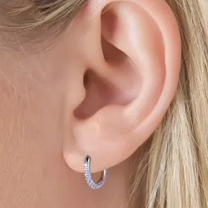 Close-up van een kristallen hoepeloorbel gedragen op de oorlel, piercing detailfoto.