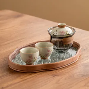 Service à thé Kung Fu portable avec théière en verre, deux tasses florales et plateau en bois.