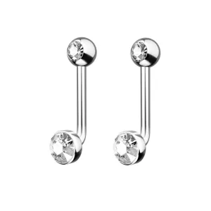 Primo piano dettagliato su gioielli per piercing bilanciere curvo in titanio con cristalli.