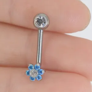 Dettaglio gioiello piercing corpo in titanio con fiore blu e design in cristallo