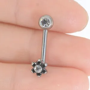 Primo piano dettagliato di piercing ricurvo in titanio con design floreale scintillante.