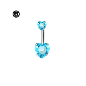 Λεπτομερές κοντινό πλάνο piercing αφαλού από τιτάνιο G23 με λαμπερά μπλε ζιργκόν σε σχήμα καρδιάς.