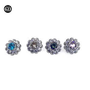 Close-up detailweergave van vier titanium bloem piercing tops met kristalstenen.