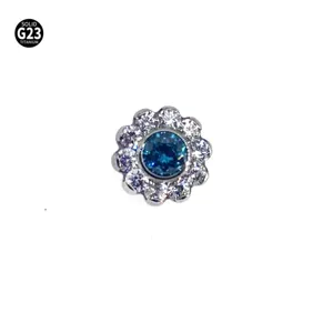 Detailopname van titanium zonnebloem piercing topje met blauwe en witte stenen erin.