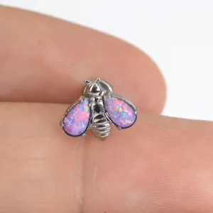 Close-up view of G23 titanium bee body piercing jewelry featuring vibrant pink opal wings.