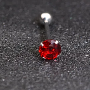 Body piercing jewelry close up showing red round zircon stone tongue bar with metal ball top.
