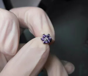 Flower body piercing jewelry with purple cubic zirconia and clear center stone detail shot.