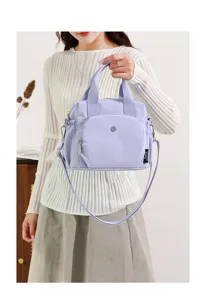 Détail du sac à bandoulière en nylon léger avec double poignée et sangle réglable au dos.