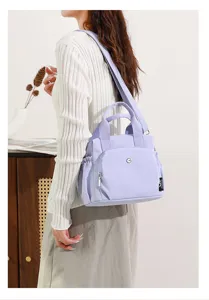 Vue détaillée d'un élégant sac à main en nylon mauve clair pour femmes avec poignées doubles.