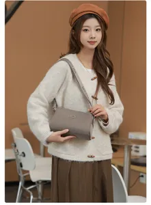 Close-up view of a stylish grey shoulder bag worn by model, showing strap and material details.