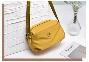 Yellow nylon crossbody bag detail view showing multi-layer design and branded strap