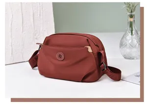 Detail view of stylish nylon crossbody shoulder bag with multiple zipper layers and strap.