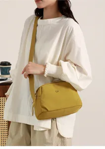 Detail view of casual yellow nylon crossbody shell shoulder bag with wide strap.