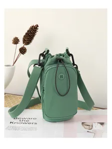 Green mini crossbody bag detail, drawstring closure, adjustable strap, daily casual style.