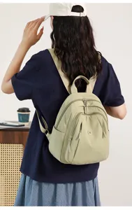 Close-up back view of a casual sage green nylon backpack with multiple zipper compartments.