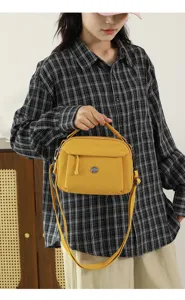 Detail view of the yellow casual nylon crossbody bag with multi-layer pockets and strap.
