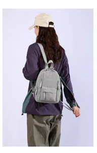 Detailed back view of casual grey mini backpack worn by model, multi-pocket design style.