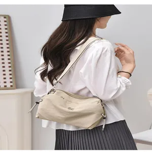 Detail view of lightweight nylon crossbody shoulder bag in beige, casual daily wear style.