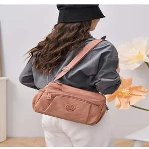 Detailed view of the pinkish-brown nylon crossbody bag with multi pockets and adjustable strap.