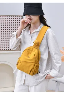 Detail view of the yellow nylon mini backpack, showing fine fabric texture, pocket and strap.