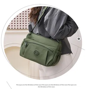 Detail view of women casual nylon crossbody bag with multi-pockets and green fabric material.