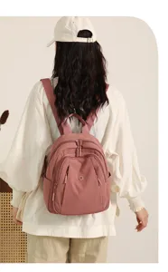 Pink nylon backpack detail showing front zipper pocket, shoulder straps, and casual style.