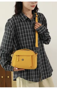 Detailed view of the stylish yellow multi-layer casual crossbody bag worn by model.