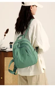 Detail view of casual sage green nylon backpack featuring multiple zip compartments and straps.