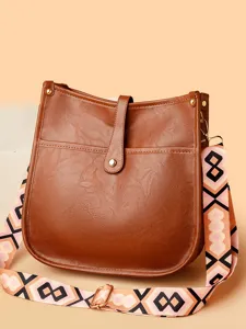 Brown faux leather messenger bag with trendy geometric strap, stylish crossbody shoulder bag.
