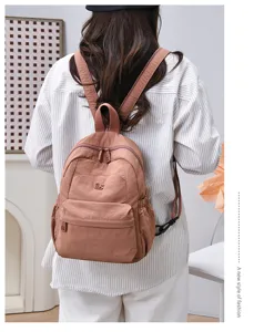 Detail shot of casual pink nylon backpack with front pocket and adjustable straps.