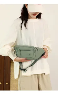Detail shot of a casual women's nylon waist bag in sage green, featuring multi-zipper pockets.