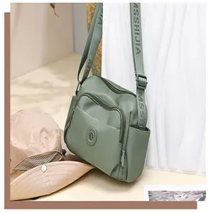 Nylon crossbody bag detail showcasing multi-pocket design, adjustable strap, and texture.