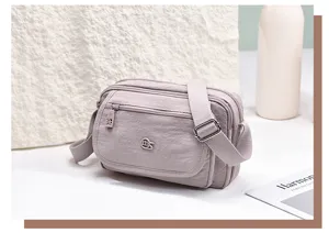 Details of the multi-layer lightweight nylon cross-body bag showing texture, zipper, and strap.