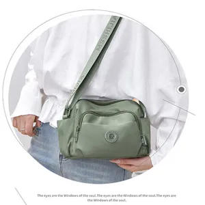 Detail view of green nylon crossbody bag with multi-pocket design and wide shoulder strap.