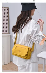 Detail view of a stylish multi-layer nylon crossbody shoulder bag in vibrant yellow.