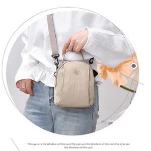 Detail view of lightweight nylon crossbody bag in beige, featuring multi-layer storage.