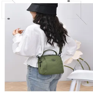 Versatile nylon crossbody bag for women, casual multi-layer shoulder bag with top handle.