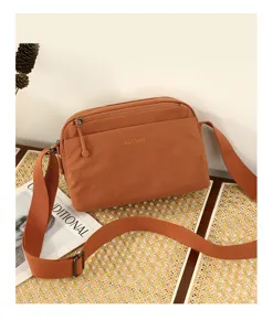 Dettaglio borsa tracolla casual, tessuto marrone leggero, cinghia regolabile, look chic.