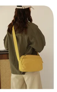 Primo piano della borsa a tracolla gialla in tessuto casual, con ampia tracolla e zip.
