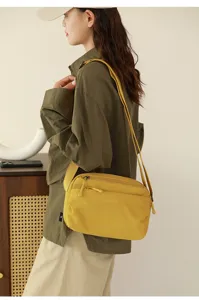 Vista dettagliata della borsa a tracolla in tela gialla, indossata dalla modella, con zip.