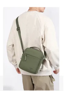 Detailed shot of the casual green oxford cloth messenger bag worn crossbody on male model.