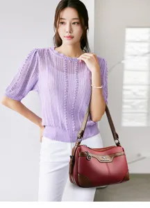 Detailed view of women leather shoulder bag, fine stitching, stylish red and brown tone.