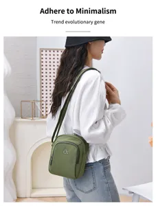 Detailed view of the green nylon crossbody bag showing fine stitching and multi-layer pockets.