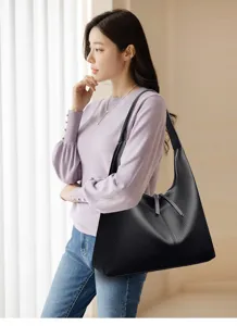 Detailed view of the stylish black leather shoulder bag worn by a model in a clean indoor setting.