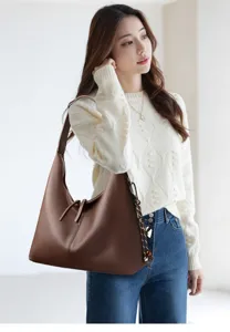 Detailed view showcasing the stylish textured brown leather hobo shoulder bag on model.