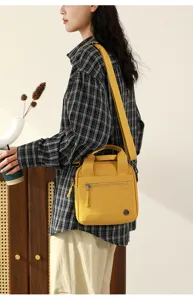 Detailed shot of yellow canvas crossbody shoulder bag with zipper pocket and top handle.