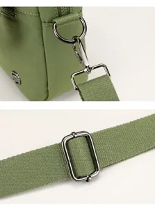 Detail shot of green canvas crossbody bag hardware, adjustable strap buckle and metal ring.
